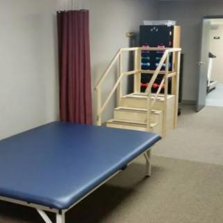 A physical therapy room equipped with a treatment table and exercise stairs for rehabilitation exercises.