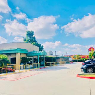 A sunny day at a hotel entrance with clear blue skies and fluffy clouds overhead.