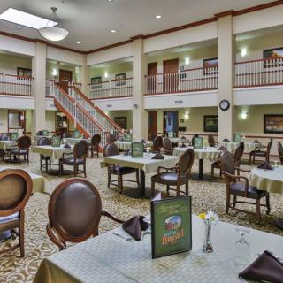 A spacious and elegantly decorated dining area with multiple tables and chairs, well-lit by overhead lighting.