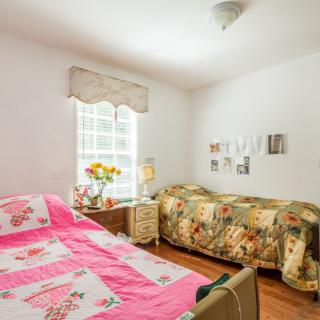 A cozy bedroom with twin beds featuring colorful bedding and natural light streaming through the window.