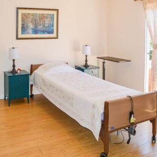 A minimalist bedroom with a hospital bed and wooden flooring.