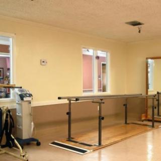 A rehabilitation room featuring parallel bars and exercise equipment.