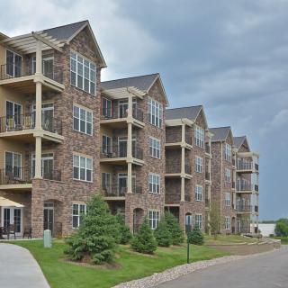A series of modern apartment buildings with brick exteriors and multiple balconies under a cloudy sky.