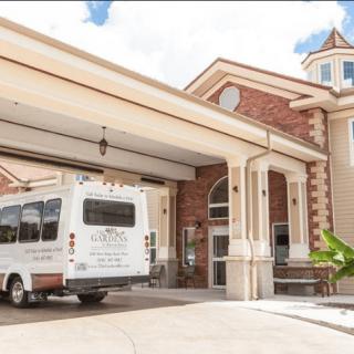 A shuttle bus parked under the entrance awning of a large building with ornate architectural details.