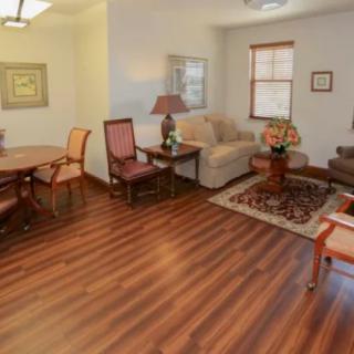 A cozy living room with hardwood floors, featuring a sofa and chairs around a coffee table.