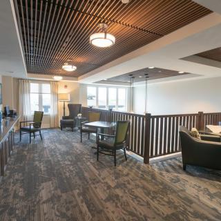 A modern lounge area featuring a wooden ceiling, comfortable seating, and tables.