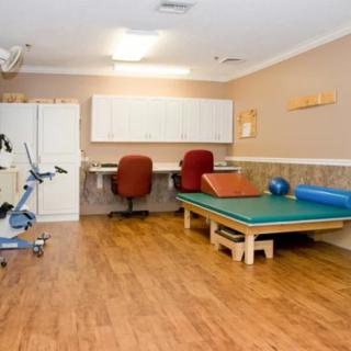 A physical therapy room with exercise equipment and a wooden floor.