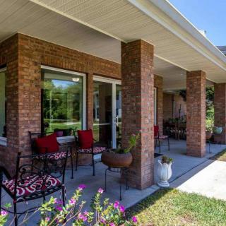 A cozy porch with brick walls, outdoor furniture, and garden views.