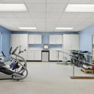 A well-equipped physical therapy room with exercise machines and parallel bars.