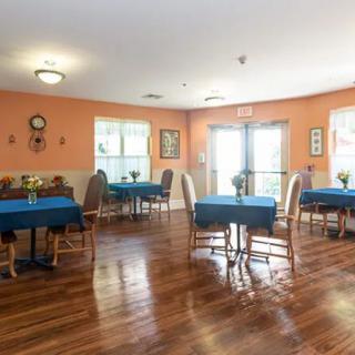 A cozy dining room with several tables and chairs, featuring wooden flooring and bright lighting.