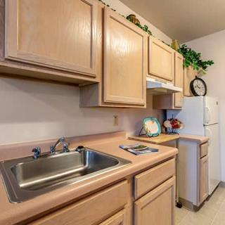 A compact kitchen setup featuring wooden cabinets, a sink, and appliances.
