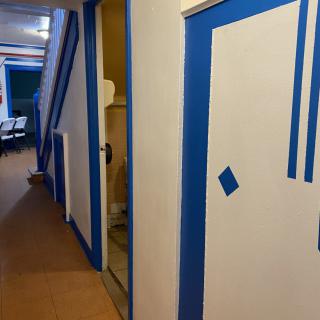 A hallway under renovation with blue tape outlining doors and walls.