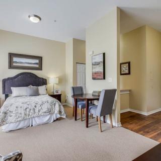 A cozy bedroom with a bed, chairs, and a small table.
