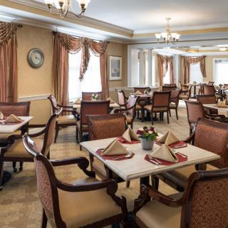 An elegant dining room with neatly arranged tables and chairs, featuring classic decor and place settings.