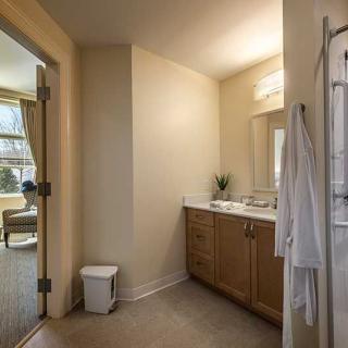 A modern bathroom with a wooden cabinet, sink, large mirror, and soft lighting.