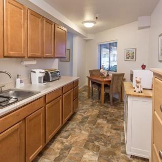 A cozy kitchen and dining area featuring wooden cabinets, a small dining table with chairs, and various kitchen appliances.