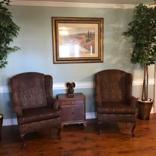 A cozy seating area with two armchairs, a side table, and decorative indoor plants.