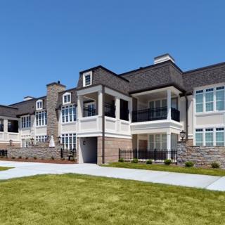 A modern luxury residential building with manicured lawns and a classic architectural style.