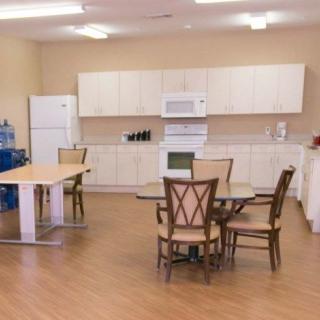A clean and organized kitchen and dining area with tables, chairs, and appliances.