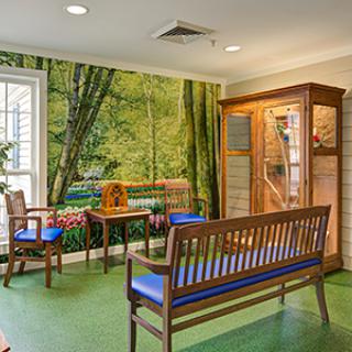 A cozy waiting room with wooden benches, a forest-themed mural, and warm lighting.