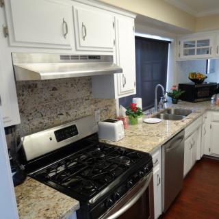 A modern kitchen with a gas stove, white cabinets, and granite countertops.