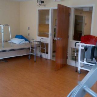 An empty hospital room with a bed, walker, and medical equipment.