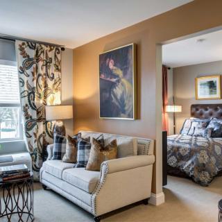 A cozy living room adjoining a bedroom, featuring elegant decor and warm tones.