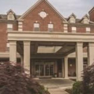 A brick building with a large entrance and columns, surrounded by trees.