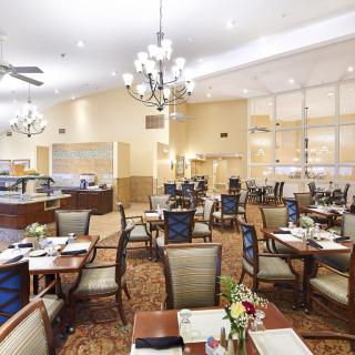 A spacious and elegantly decorated restaurant dining area with neatly arranged tables and chairs under chandeliers.