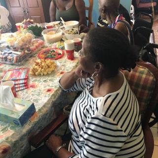 A group of people sitting around a table filled with food, enjoying a social gathering.