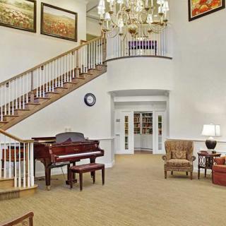 A spacious foyer with a grand staircase, a piano, and elegant furnishings.