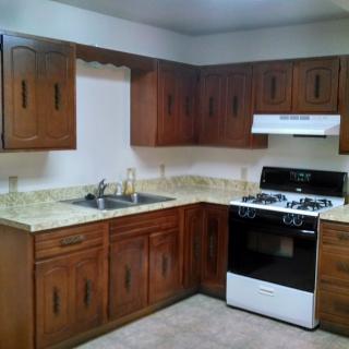 A kitchen interior featuring wooden cabinets, a stove, and a sink.
