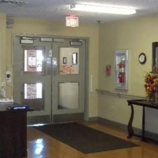 A view of an indoor entrance hallway with double doors and a fire extinguisher on the wall.