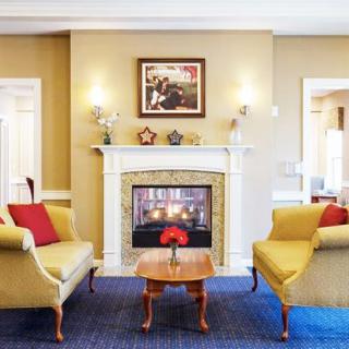 A cozy living room with a central fireplace, surrounded by elegant armchairs and tasteful decor.