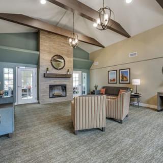A cozy living room with a vaulted ceiling, featuring a stone fireplace and comfortable seating.
