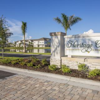 Entrance sign to a residential community with palm trees and well-maintained landscaping.