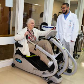 An elderly patient engages with exercise equipment under the supervision of a medical professional, highlighting the importance of rehabilitation in healthcare settings.
