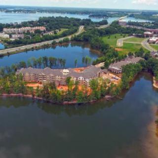 Aerial view of a residential building surrounded by a lake and trees.