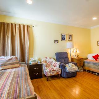 A cozy bedroom with two beds, a recliner chair, and warm lighting.