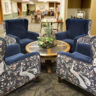 A cozy lounge area featuring a set of four blue and patterned armchairs surrounding a round table with a decorative plant centerpiece.