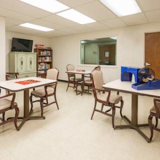 A well-lit room featuring tables and chairs, designed for meetings or group activities.