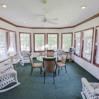 A bright sunroom with wicker furniture and large windows.