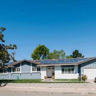A suburban house equipped with solar panels under a clear blue sky.