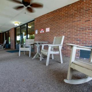 A cozy patio area with rocking chairs and a table against a brick wall.