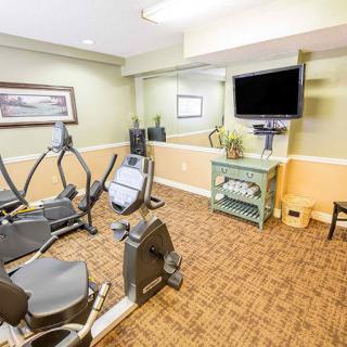 A small fitness room with exercise bikes, a television, and a mirror.