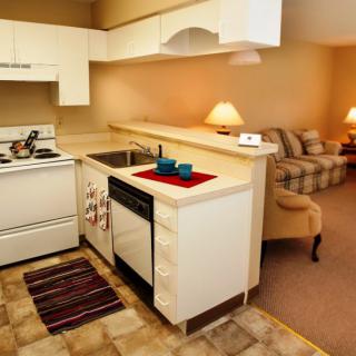 A cozy apartment with an open kitchen and living area, featuring white cabinets and modern furnishings.
