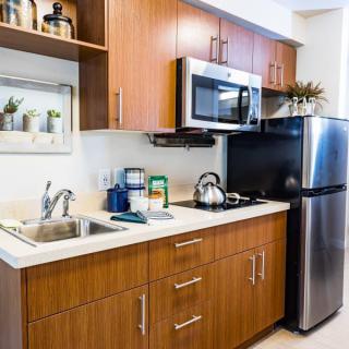 A modern kitchen with wooden cabinets, a microwave, refrigerator, and a neatly organized countertop.