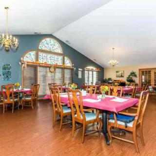 A spacious dining area with elegantly set tables and large windows, illuminated by chandeliers.