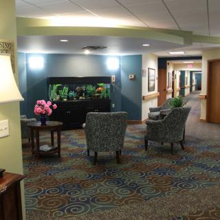 A cozy lobby interior featuring a seating area with two chairs and a fish tank, illuminated by indoor lighting.