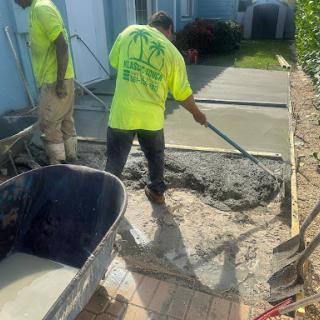 Workers pouring and spreading concrete for a new surface installation.